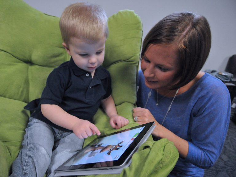 A child using a tablet at home with a parent nearby